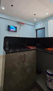 a kitchen with a black counter and a tv on the wall at Royal inn in Patna