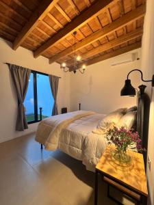ein Schlafzimmer mit einem Bett und einem Tisch mit Blumen darauf in der Unterkunft Farrell Jardin - Casco Historico in San Antonio de Areco