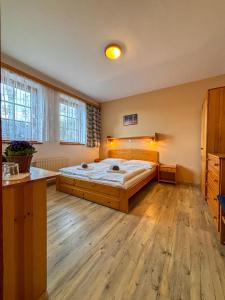Penzion U Studeného potoka في نوفي هوتو: غرفة نوم بسرير كبير وأرضية خشبية