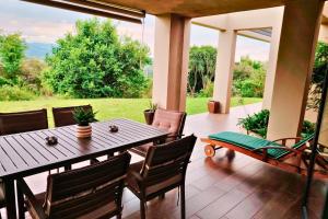 een houten tafel en stoelen op een patio met uitzicht bij Dierama Dream Cathkin Estates in Ardmore