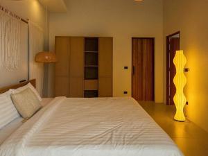 a bedroom with a large white bed and a lamp at Cocolane Villa 2 in Ban Madua Wan +4 photos