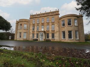 een oud gebouw met een weerspiegeling in een plas water bij Frenchay Park House in Bristol