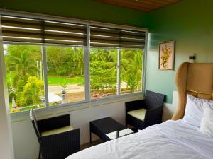 SaraTUBURAN Poolside的一间卧室，有一张床、两把椅子和一扇窗户