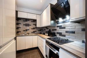 a kitchen with white cabinets and a stove at Stunning 3 Bedroom Home in Newcastle-under-Lyme with Garden in Newcastle under Lyme +16 photos