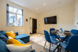 a living room with a blue couch and a table at Stunning 3 Bedroom Home in Newcastle-under-Lyme with Garden in Newcastle under Lyme