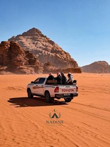 een groep mensen achterin een vrachtwagen in de woestijn bij Nadine Luxury Camp in Wadi Rum +4 foto's