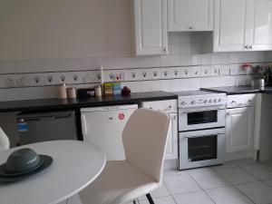 A Four Bedroom House في Tettenhall: مطبخ بأجهزة بيضاء وطاولة عليها قبعة