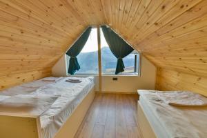 Dos camas en una habitación con una gran ventana. en Gudauri Private Cottage 2, en Gudauri