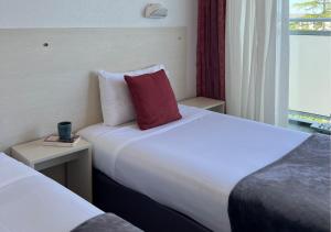 a hotel room with two beds and a red pillow at Logis Le Gavrinis in Baden +14 photos