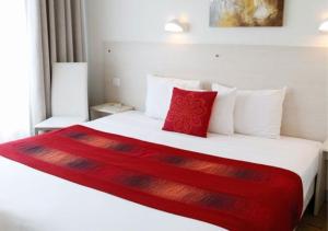 a bedroom with a large white bed with red pillows at Logis Le Gavrinis in Baden