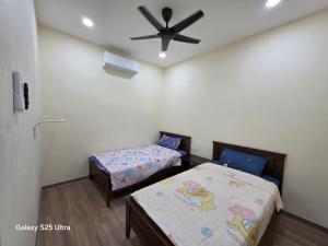Un dormitorio con dos camas y un ventilador de techo. en Bliss Homestay, en Simpang Ampat