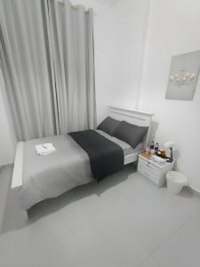 a white bedroom with a bed and a sink at Flora Residence in Abu Dhabi