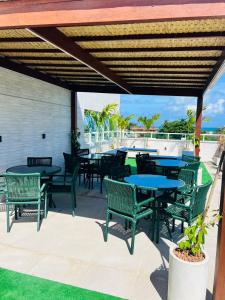 a patio with tables and chairs and a view of the ocean at La Coruña Flat Makaranduba in Porto De Galinhas +41 photos