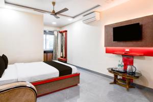 Super Townhouse Lake Town Clock Tower Formerly Crown Comfort في Pātipukur: غرفة نوم مع سرير وتلفزيون بشاشة مسطحة