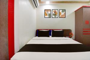 Super Townhouse Lake Town Clock Tower Formerly Crown Comfort في Pātipukur: غرفة نوم بسرير في غرفة حمراء وبيضاء