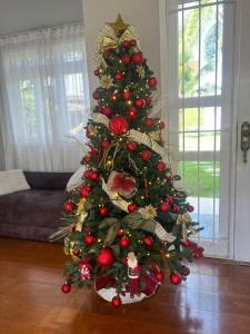 a christmas tree with ornaments on it in a living room at Casa Premium para Natal e Ano Novo in Joinville