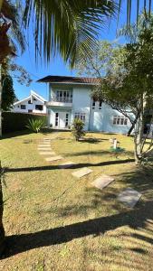 a white house with a palm tree in front of it at Casa Premium para Natal e Ano Novo in Joinville