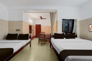 um quarto com duas camas e uma cadeira em Hotel O Rock Beachview Pondicherry Formerly Varsha Residency em Pondicherry