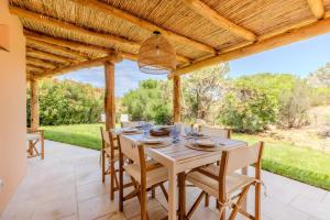 uma mesa de madeira e cadeiras sob uma pérgola de madeira em Apartment In Porto Cervo em Porto Cervo