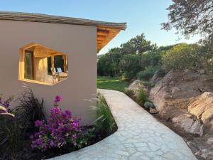um jardim com flores roxas ao lado de um edifício em Apartment In Porto Cervo em Porto Cervo