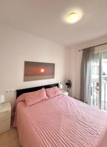 Un dormitorio con una cama con una manta rosa. en Apartamento poleo, en Benalmádena