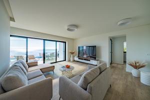 un soggiorno con due divani e una televisione di Villa Infinityviews Madeira a Câmara de Lobos