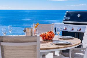 a table with wine glasses and a stove with the ocean at Villa Infinityviews Madeira in Câmara de Lobos