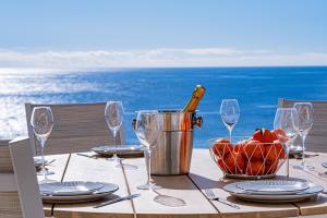 a table with a bottle of wine and glasses on the beach at Villa Infinityviews Madeira in Câmara de Lobos