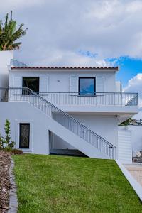 una casa bianca con scale e prato di Villa Infinityviews Madeira a Câmara de Lobos
