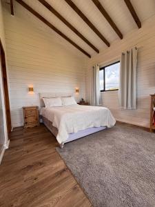 een slaapkamer met een bed en een groot raam bij Cabana Jardim das Nuvens in Urupema