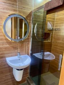 Un baño con lavabo y ducha con espejo. en Angel Hotels, en Lagos