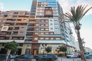 um prédio alto com carros estacionados na frente dele em Relax & Sea View à 2 Pas de la Marina em Tânger
