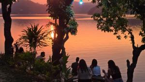 Un grupo de personas sentadas junto al agua al atardecer en Lake mirror, en Pokhara