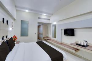 a bedroom with a large bed and a flat screen tv at Townhouse Kakinada Nagamalli Thota Junction in Kākināda