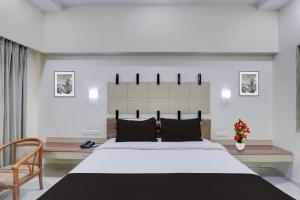 a bedroom with a large white bed and a chair at Townhouse Kakinada Nagamalli Thota Junction in Kākināda