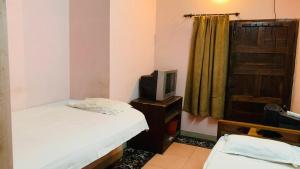 a small room with a bed and a tv at JS Homestay in Nāgercoil +10 photos