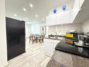 sky view apartments في سان خوان: مطبخ بخزائن بيضاء وثلاجة سوداء