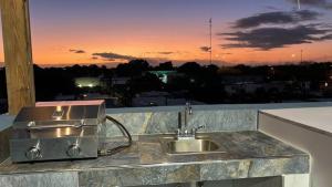 sky view apartments في سان خوان: حوض مطبخ مع غروب الشمس في الخلفية