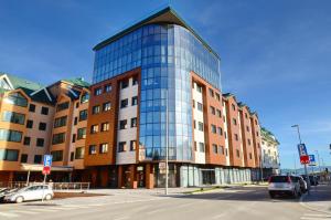a tall glass building with cars parked in front of it at Hotel Aleksandar Conference & Spa in Žabljak +59 photos
