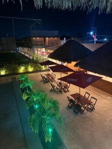 a group of tables with umbrellas and palm trees at night at Pousada Arena 165 in Murici