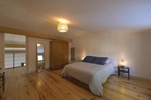 ein Schlafzimmer mit einem Bett, einer Lampe und Holzböden in der Unterkunft La maison du merle bleu in Quintillan