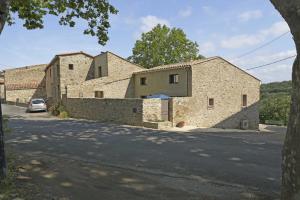 ein Steinhaus mit einer Steinmauer neben einer Straße in der Unterkunft La maison du merle bleu in Quintillan