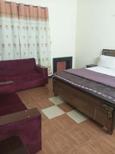 uma sala de estar com uma cama e um sofá em Hotel Grand Orchard Two em Lahore