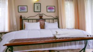Legend Safari Lodge في هراري: غرفة نوم بسرير كبير مع ملاءات بيضاء
