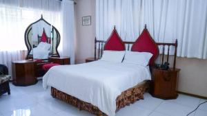 Legend Safari Lodge في هراري: غرفة نوم بسرير كبير مع وسائد حمراء