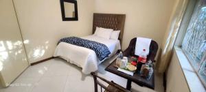 Legend Safari Lodge في هراري: غرفة نوم صغيرة مع سرير وصينية طعام