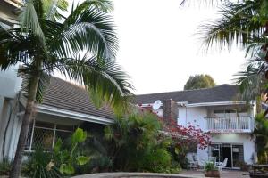 Legend Safari Lodge في هراري: منزل أمامه أشجار نخيل