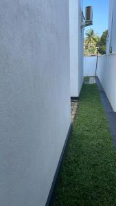 um prédio branco com grama verde ao lado de um muro em Kaushi Home em Kottawa