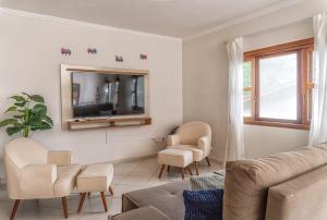 a living room with a couch and a tv at 400 m te Separam das Areias da Praia de Boraceia, casa com piscina aquecida para ate 12 pessoas in São Sebastião