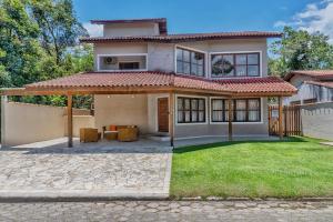 a house with a patio and a yard at 400 m te Separam das Areias da Praia de Boraceia, casa com piscina aquecida para ate 12 pessoas in São Sebastião
